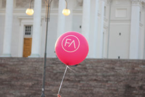 Pinkki FA:n ilmapallo heiluu ilmassa tuomiokirkon portaiden edessä.