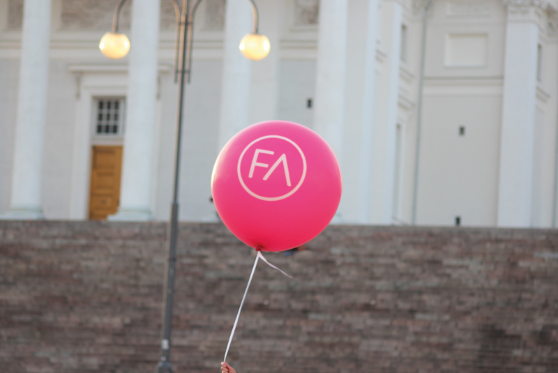 Pinkki FA:n ilmapallo heiluu ilmassa tuomiokirkon portaiden edessä.