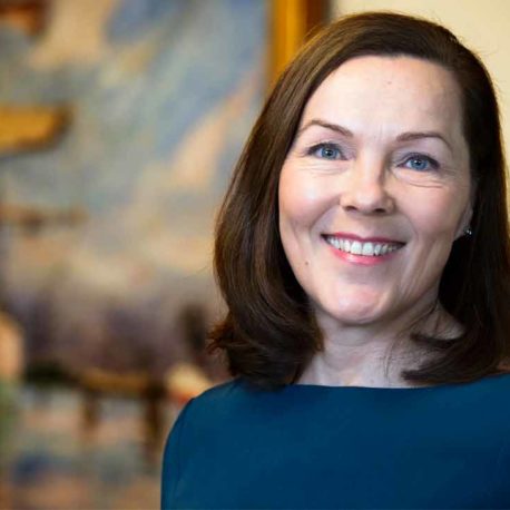 Anne-Maria Salonius katsoo sinisessä mekossa kameraan ja hymyilee.