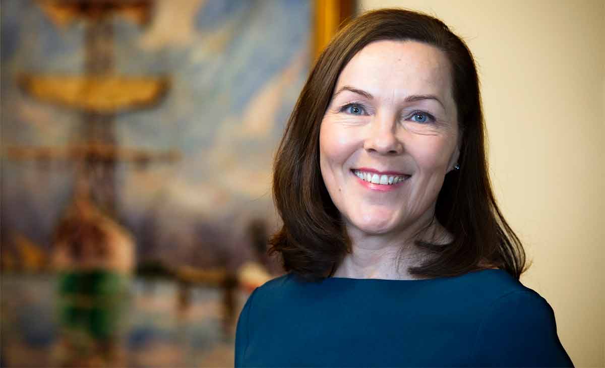 Anne-Maria Salonius katsoo sinisessä mekossa kameraan ja hymyilee.