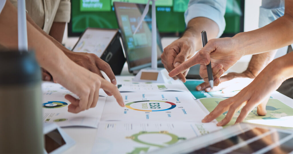 Papereita pöydällä ja käsiä osoittelemassa